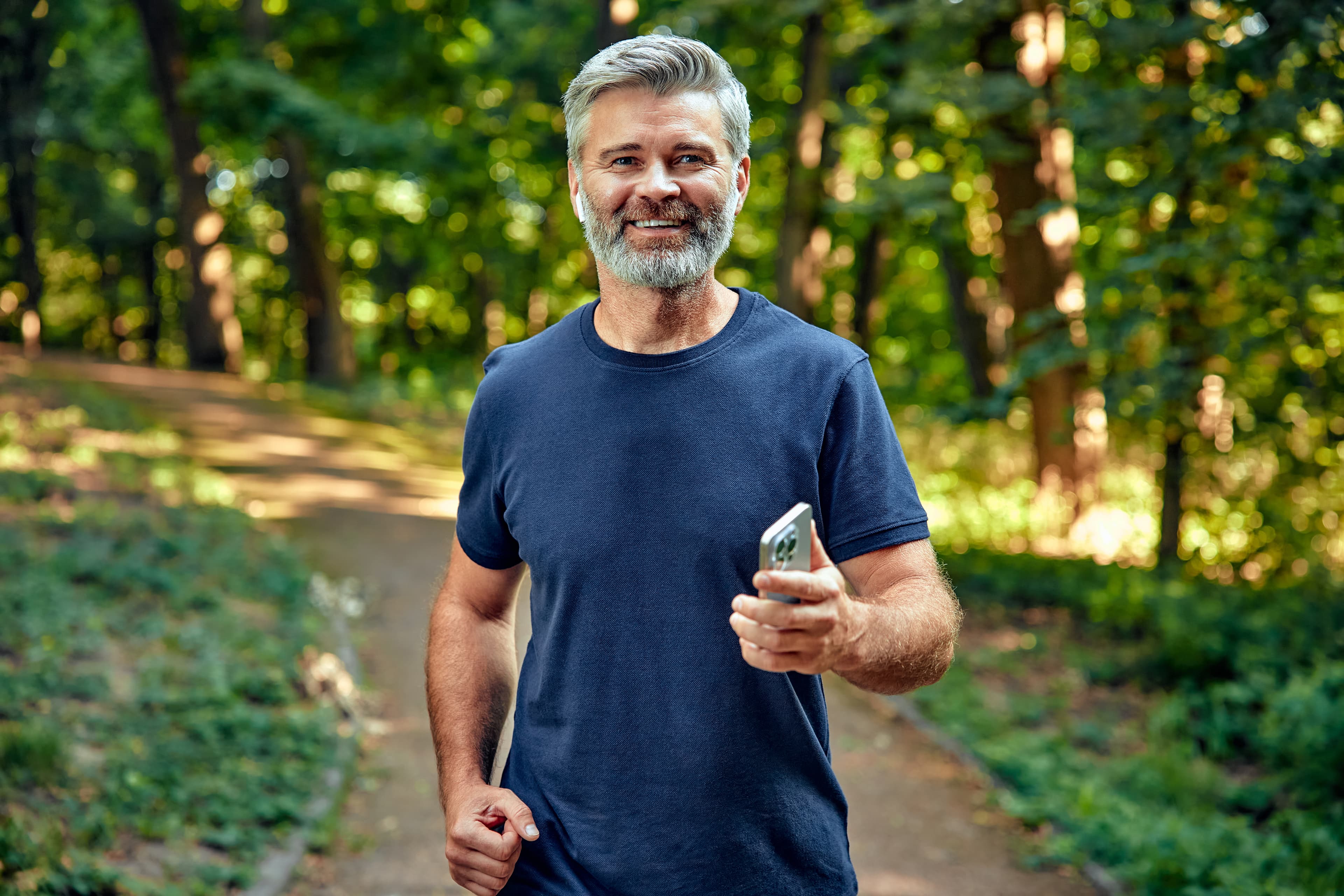 Middle-aged man jogging outdoors while listening to music