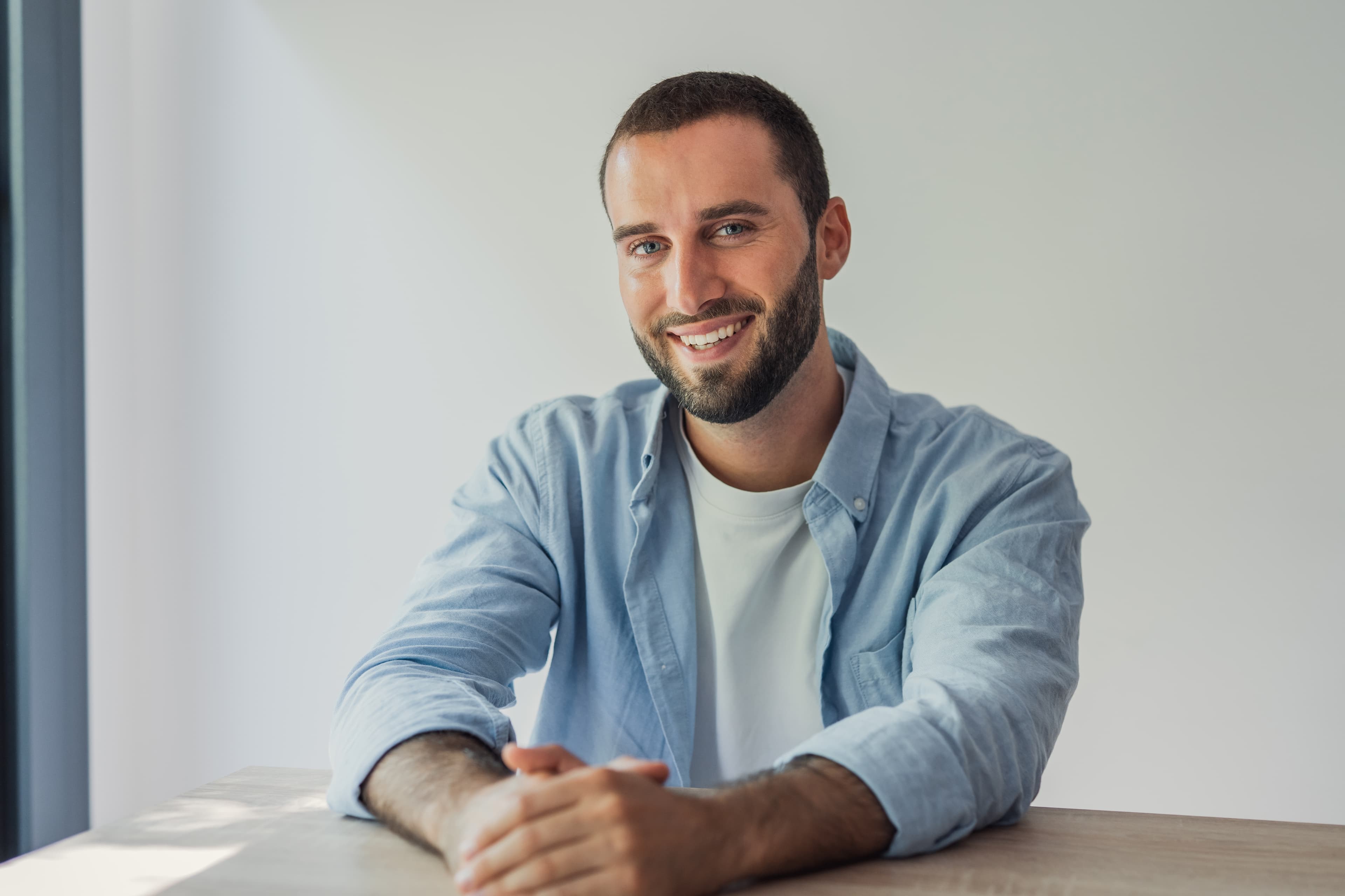 Friendly man in a blue shirt smiling at a desk