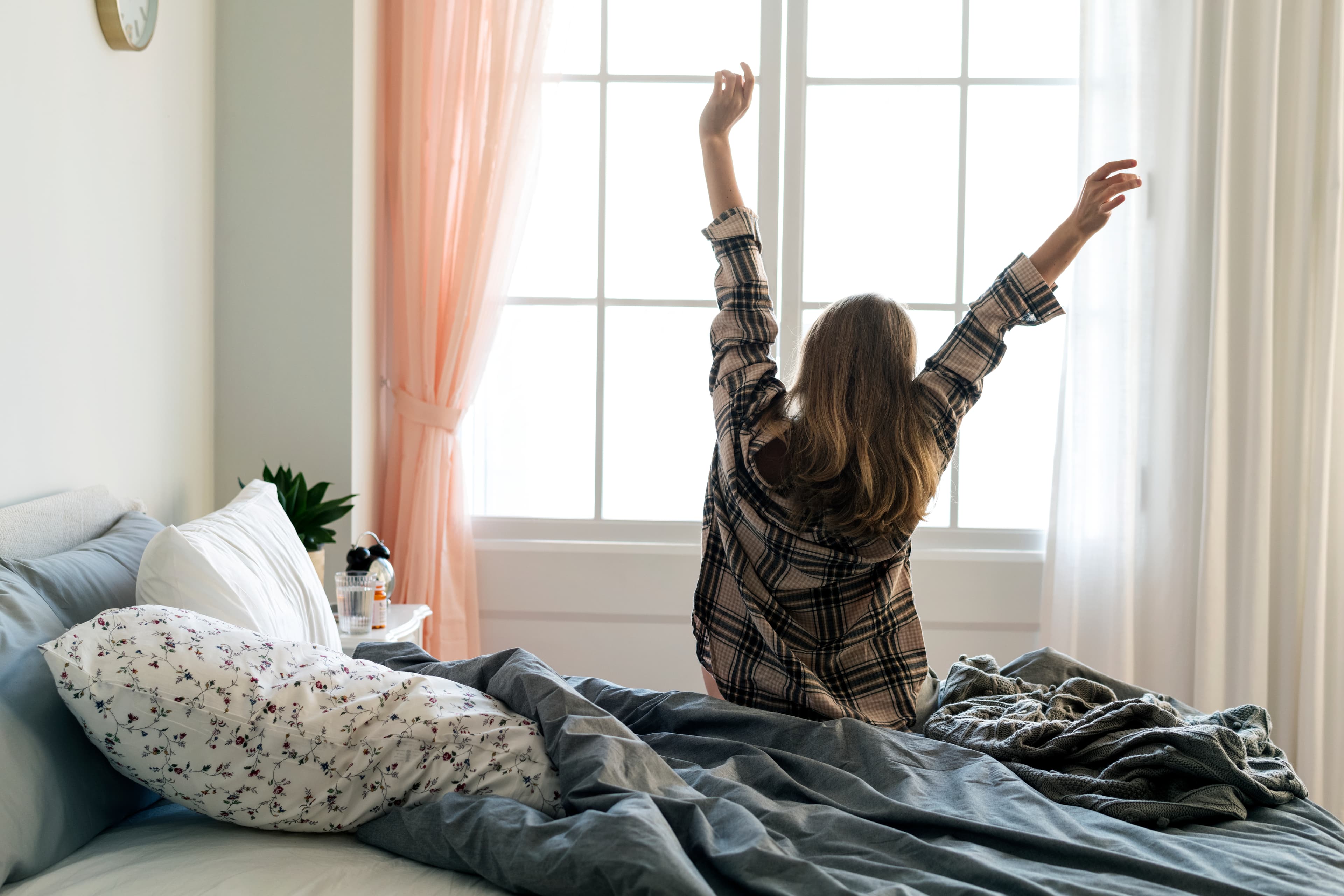 Woman stretching her arms in the morning while sitting on a bed