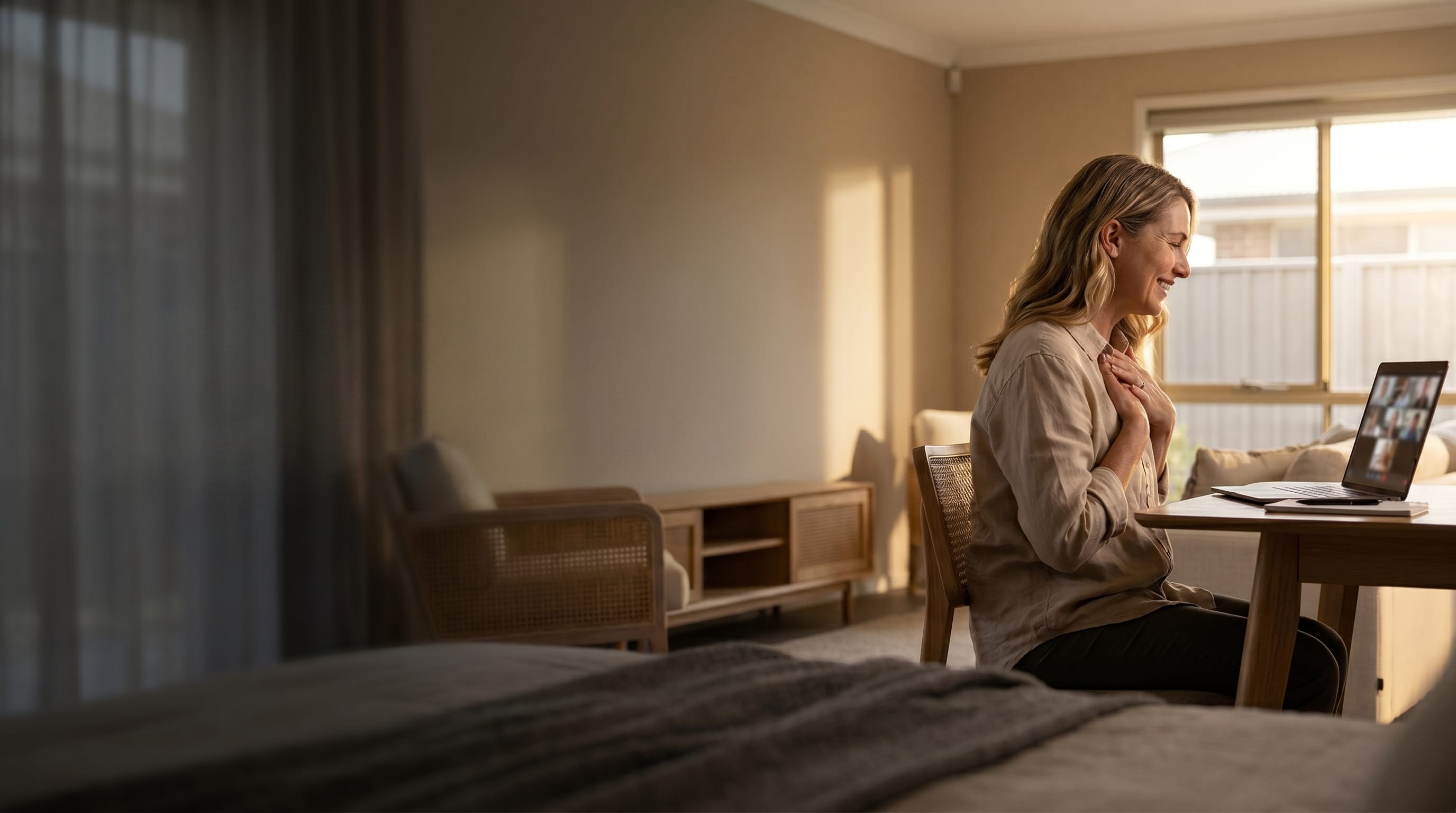 Woman at home on a video call, warm golden light, soft interior suited for headline overlay